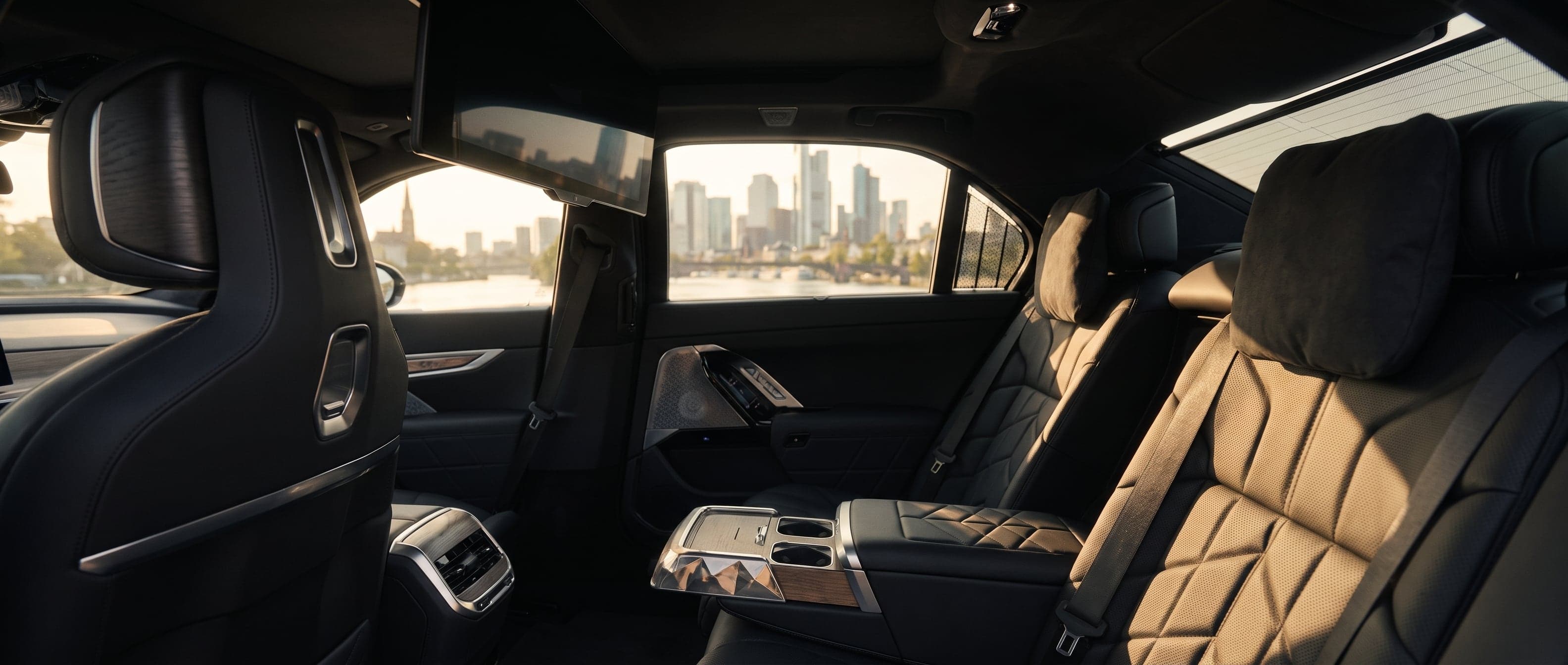 The BMW i7's rear cabin in black and cream leather with a city skyline through the window.