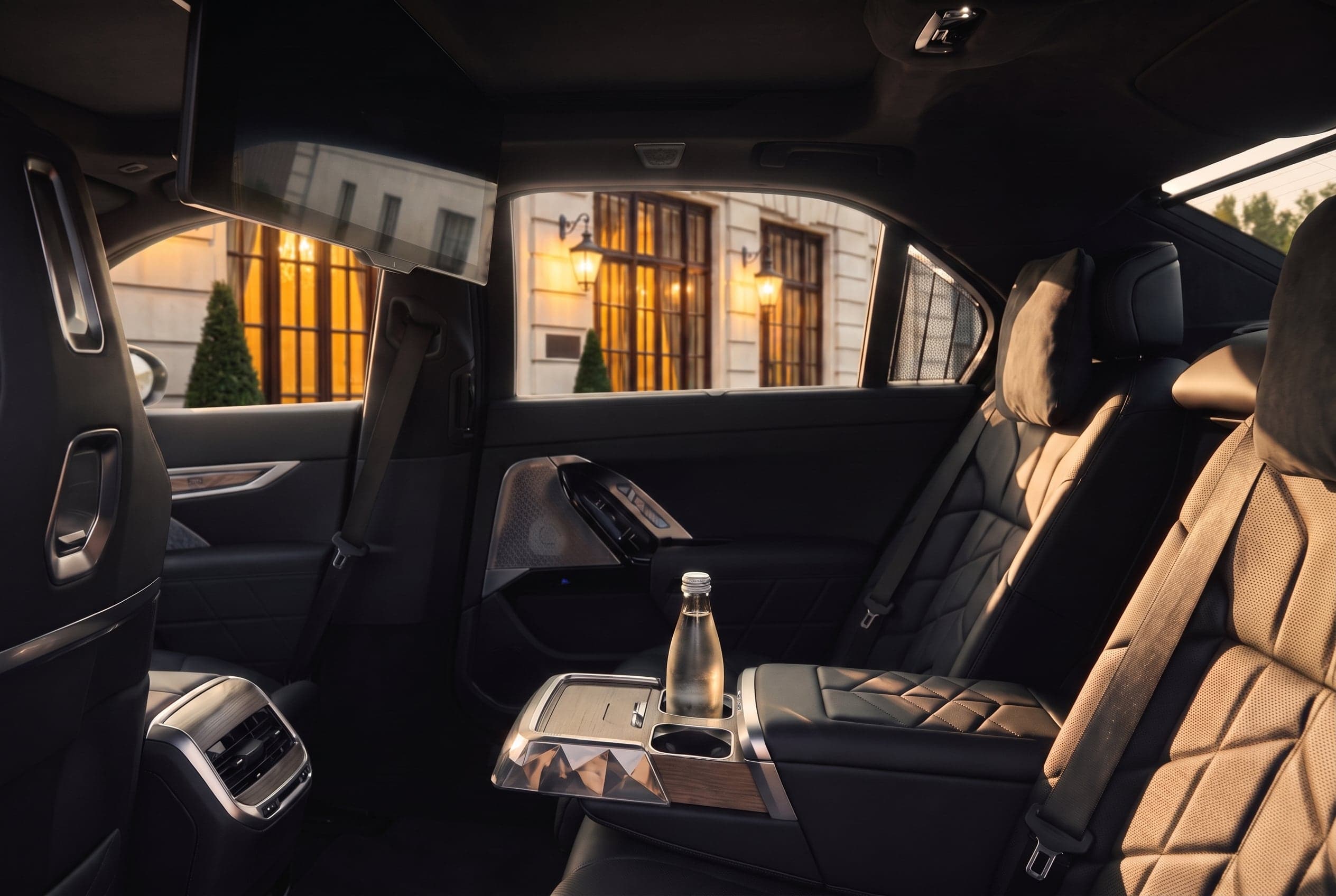 The BMW i7's rear cabin in black and cream leather with a water bottle on the console.